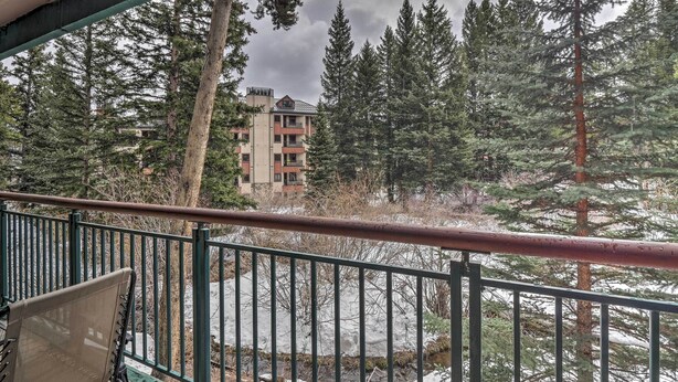 A balcony with a view of a building surrounded by tall evergreen trees. - Walk to Main St: Ski-in/ski-out Breckenridge Condo (Breckenridge)