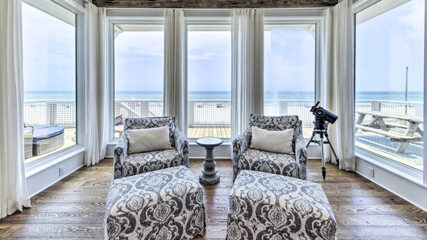 A room with large windows, a telescope, and patterned furniture.
