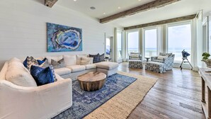 A spacious living room with a large sectional sofa, a coffee table, and a view of the ocean through large windows.