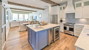 A modern kitchen with a central island, stainless steel appliances, and a wooden ceiling.