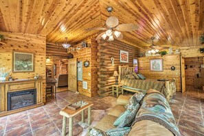 A log cabin interior with a fireplace, wooden ceiling, and a cozy living area with a sofa and a coffee table. - Log Cabin Sanctuary in Inverness w/ Furnished Deck (Inverness)