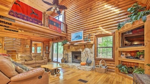 L’intérieur d’une cabane en rondins, avec une cheminée, des canapés en cuir et un plancher en bois.