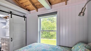 Ein Schlafzimmer mit Bett, Fenster, Nachttischlampe und Kleiderschrank.