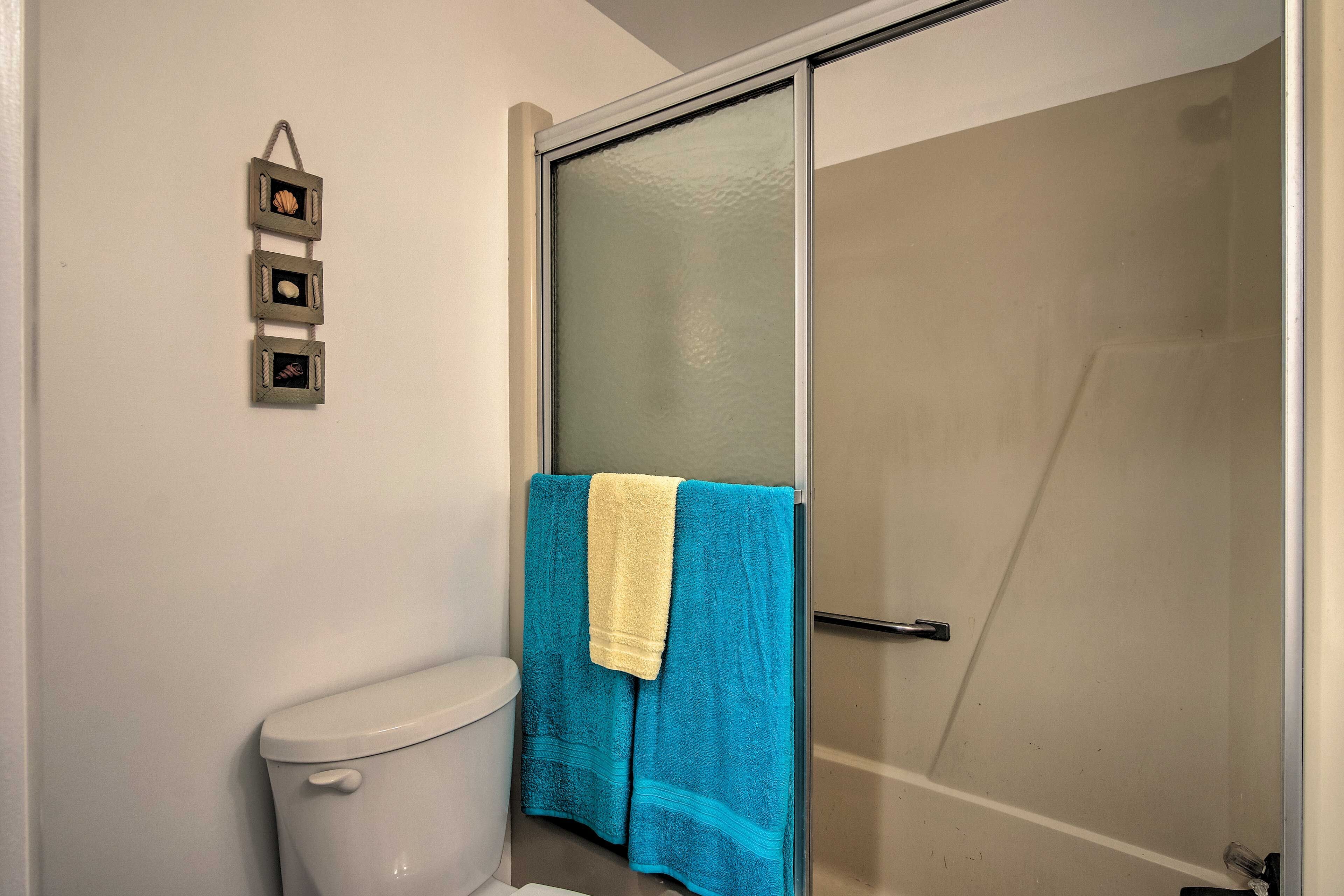 A bathroom with a toilet, a glass shower door, and a towel rack with a blue towel.