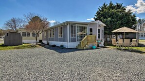 Una casa de un piso con porche cubierto, una pequeña terraza y camino de entrada de grava.