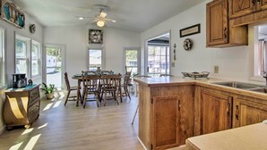 Una cocina con armarios de madera, una isla central y una zona de comedor con sillas y una mesa.
