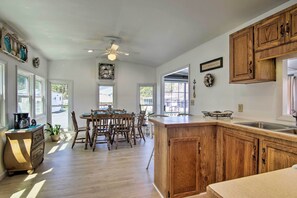 A kitchen with wooden cabinets, a central island, and a dining area with chairs and a table.