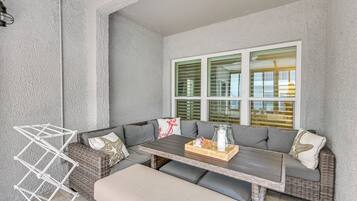 A sunlit room with a wicker sofa, a small table, and a window with blinds.