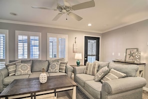 A living room with two grey sofas, a coffee table, a ceiling fan, and a door with a decorative glass panel. - Elegant FL Condo w/ Pool: Walk to Madeira Beach! (Madeira Beach)