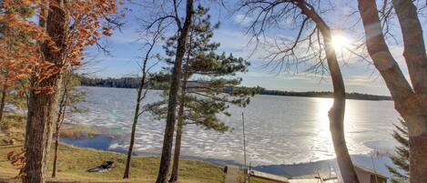 A lakeside cabin with a dock, surrounded by trees and a clear view of the lake.