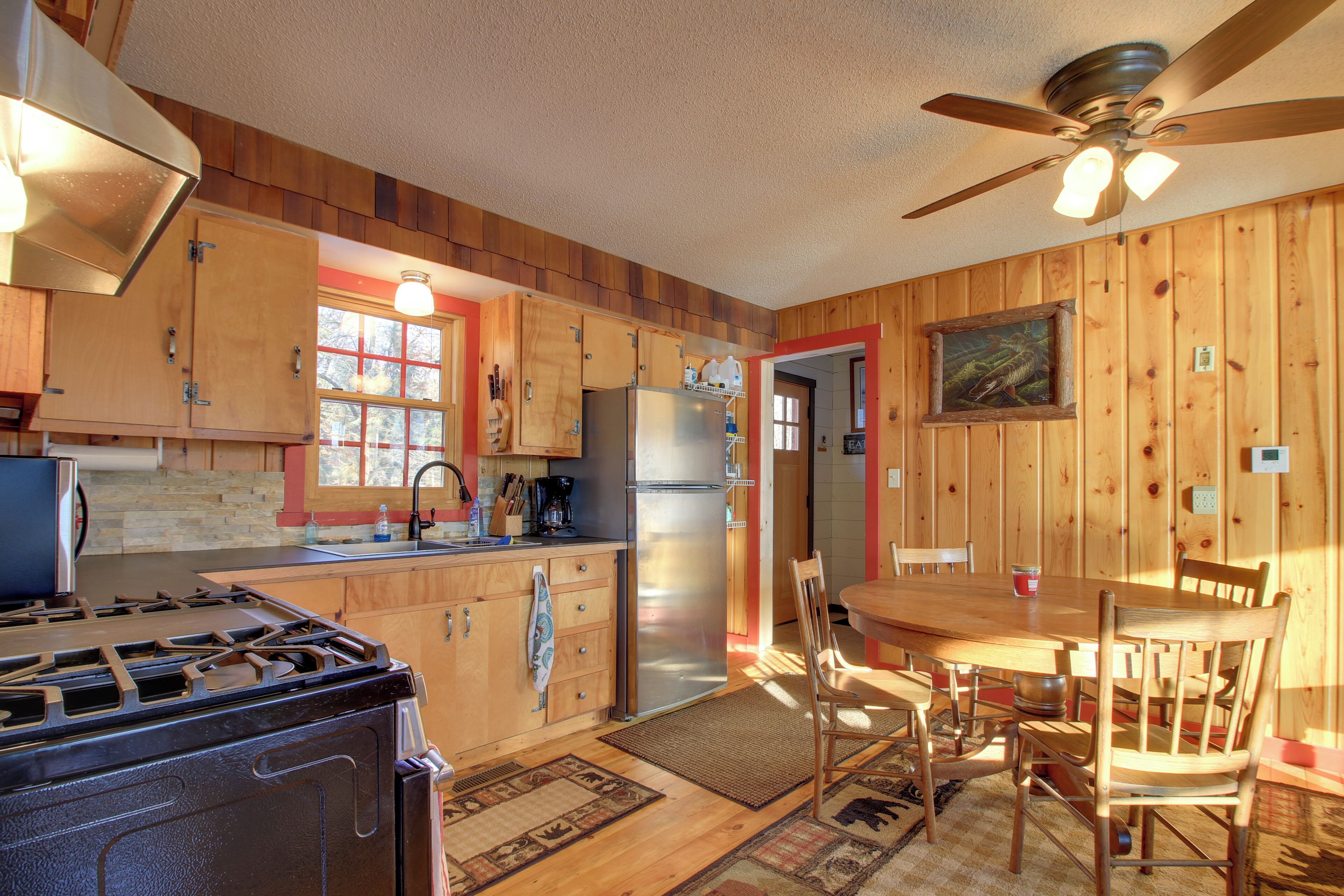 A wooden-paneled kitchen with a stove, refrigerator, and dining table with chairs.