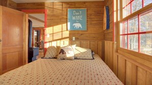 Un dormitorio de cabaña de madera con una cama, almohadas y un cartel en la pared que dice 'No despiertes al oso'.