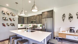 A modern kitchen with a large island, stainless steel appliances, and pendant lighting. - Hike, Ski, Golf, & Fish: Silverthorne Townhome! (Silverthorne)