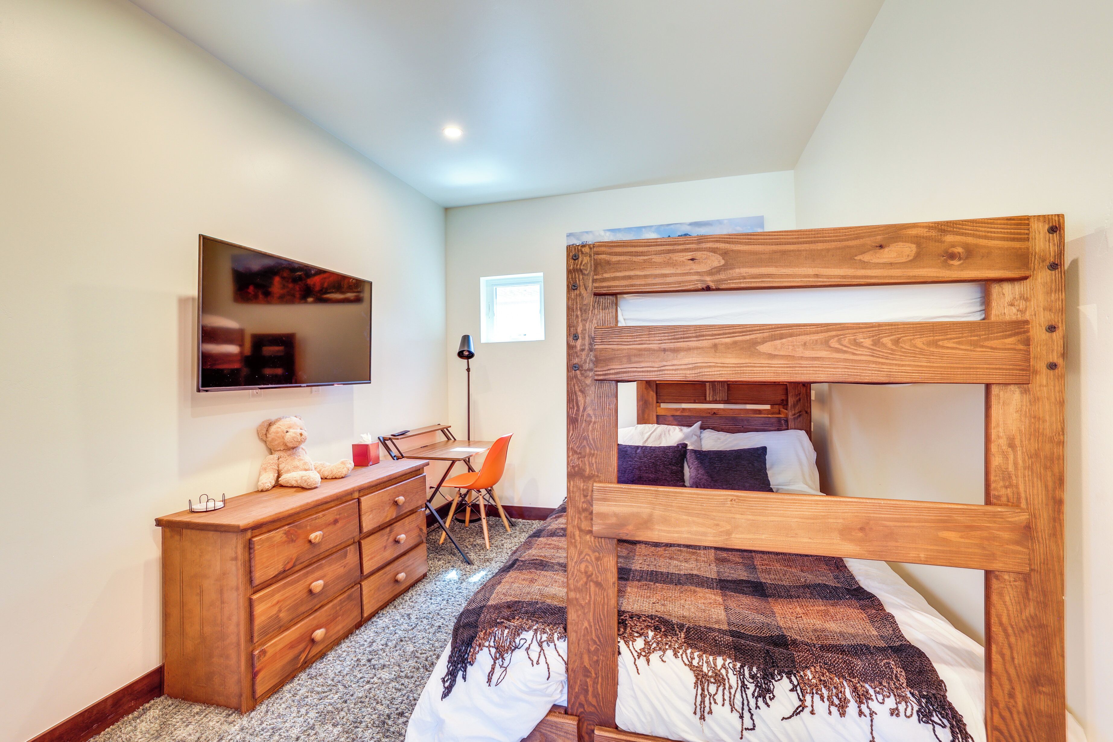 Une chambre avec un lit superposé, une commode en bois, un bureau et une chaise.
