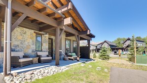 A covered outdoor seating area with stone walls and wooden beams, a stone pathway, and a view of neighboring houses. - Hike, Ski, Golf, & Fish: Silverthorne Townhome! (Silverthorne)