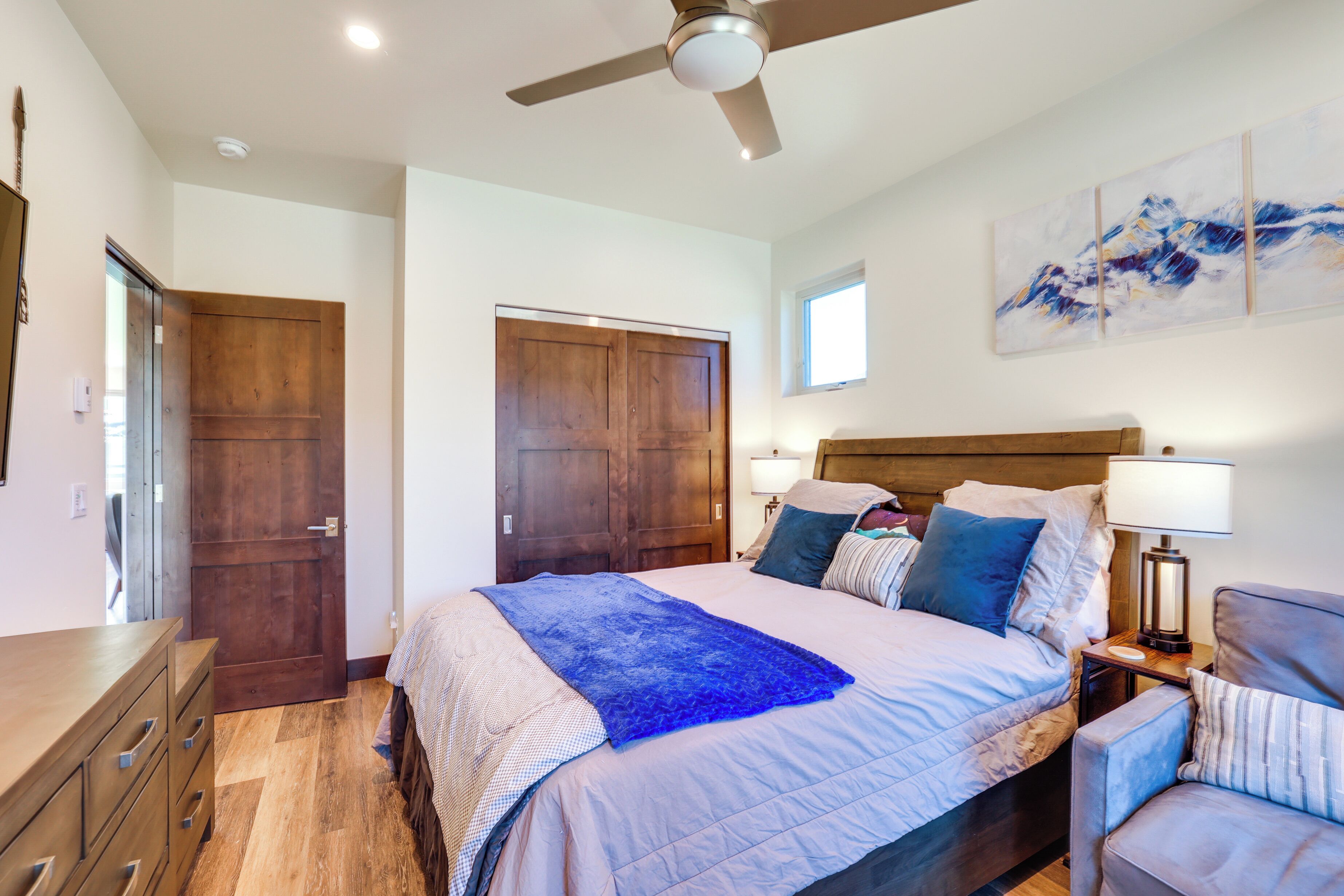 Un dormitorio con una cama grande, un armario de madera y un ventilador de techo.