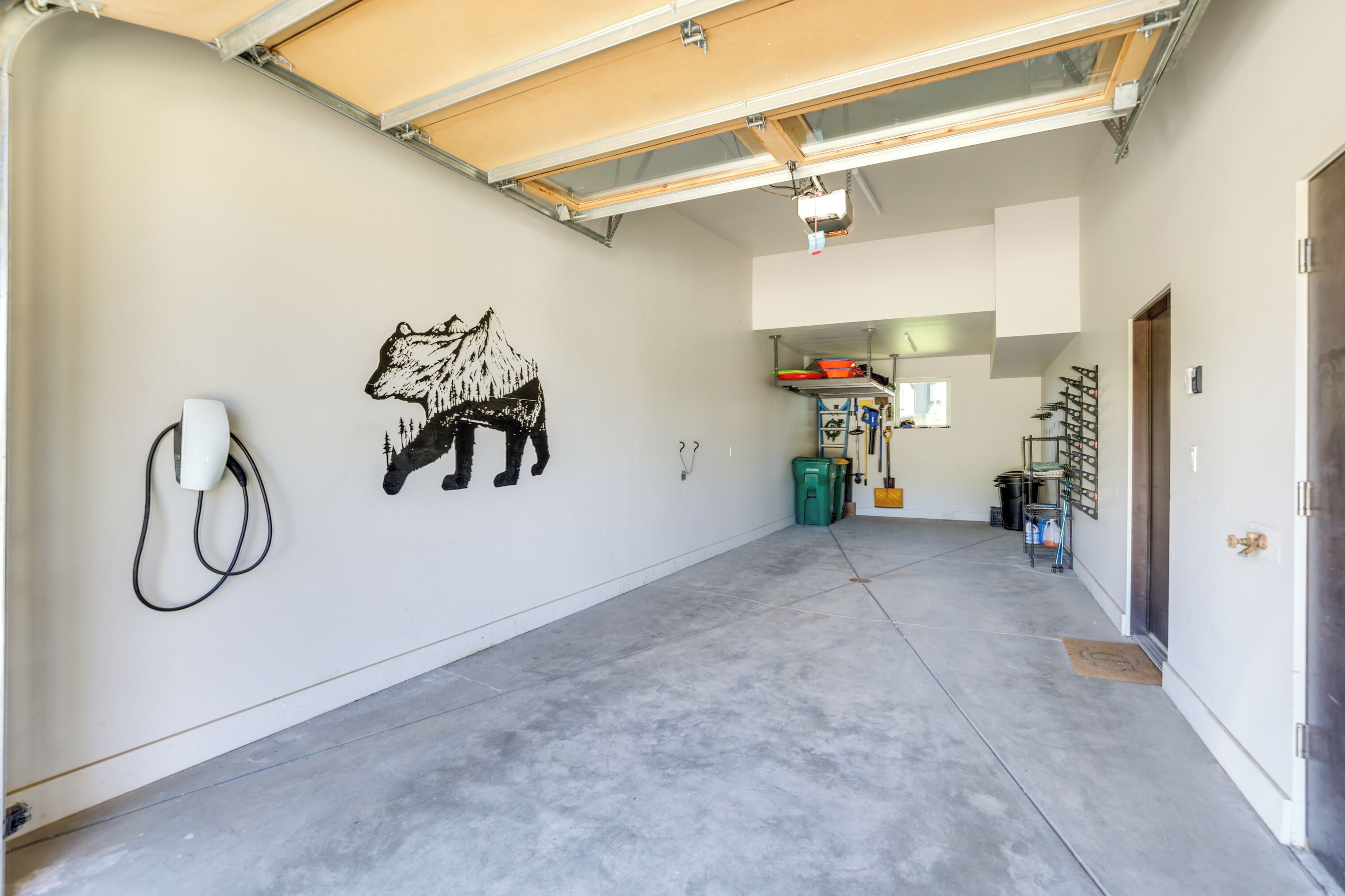 Een ruime garage met een betonnen vloer, een grote muurschildering van een beer op de muur, en een dakraam.