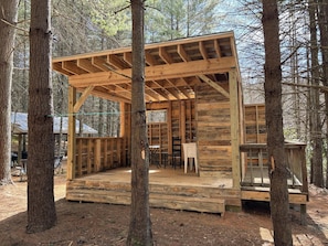 A wooden cabin with a covered porch, built into a forested area.