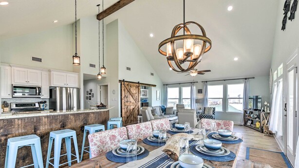 A spacious kitchen with modern appliances, a dining area with blue and white decor, and large windows offering natural light. - Surfside Beach Home w/ Views, Steps to Shore! (Freeport)