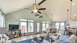 A spacious living room with a high ceiling, a ceiling fan, a television, and a dining area with chairs and a table. - Surfside Beach Home w/ Views, Steps to Shore! (Freeport)