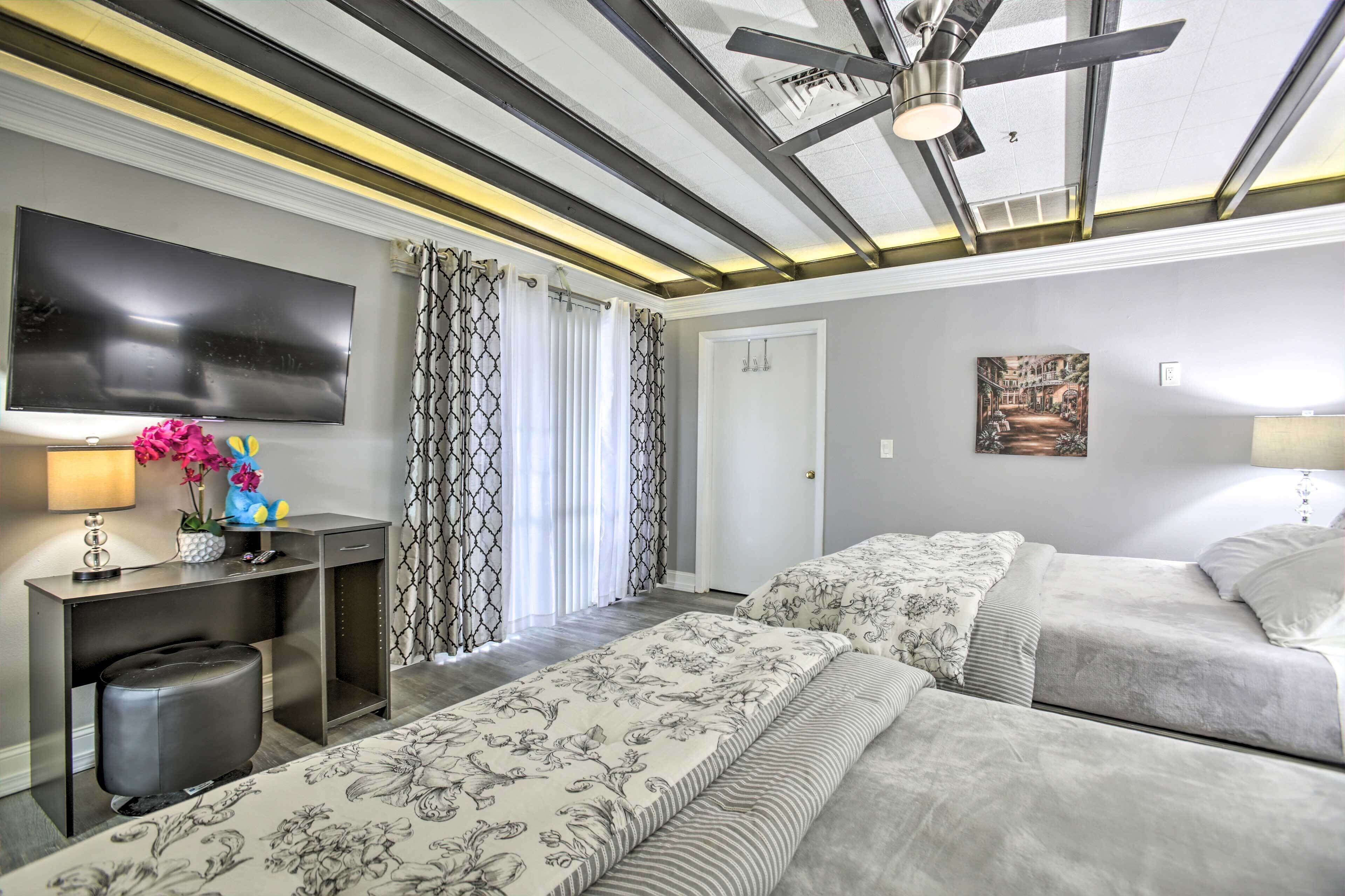Een hotelkamer met een groot bed, een bureau met een flatscreen-televisie, een plafondventilator en een schilderij aan de muur.