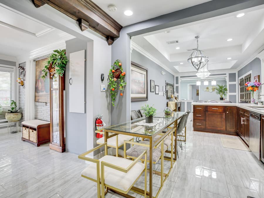 A modern kitchen with a glass dining table, wooden cabinets, and a central island.