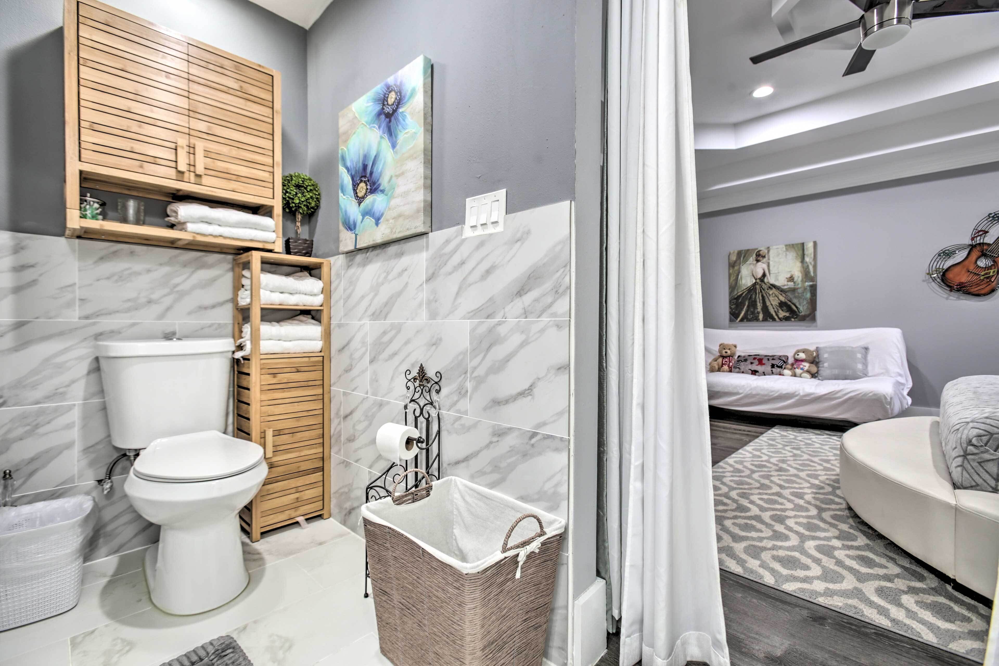 Une salle de bain moderne avec des toilettes, un meuble en bois et un panier à linge en osier.