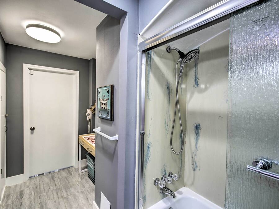 Un baño con ducha envuelta en vidrio, una bañera blanca y un tocador pequeño con espejo.