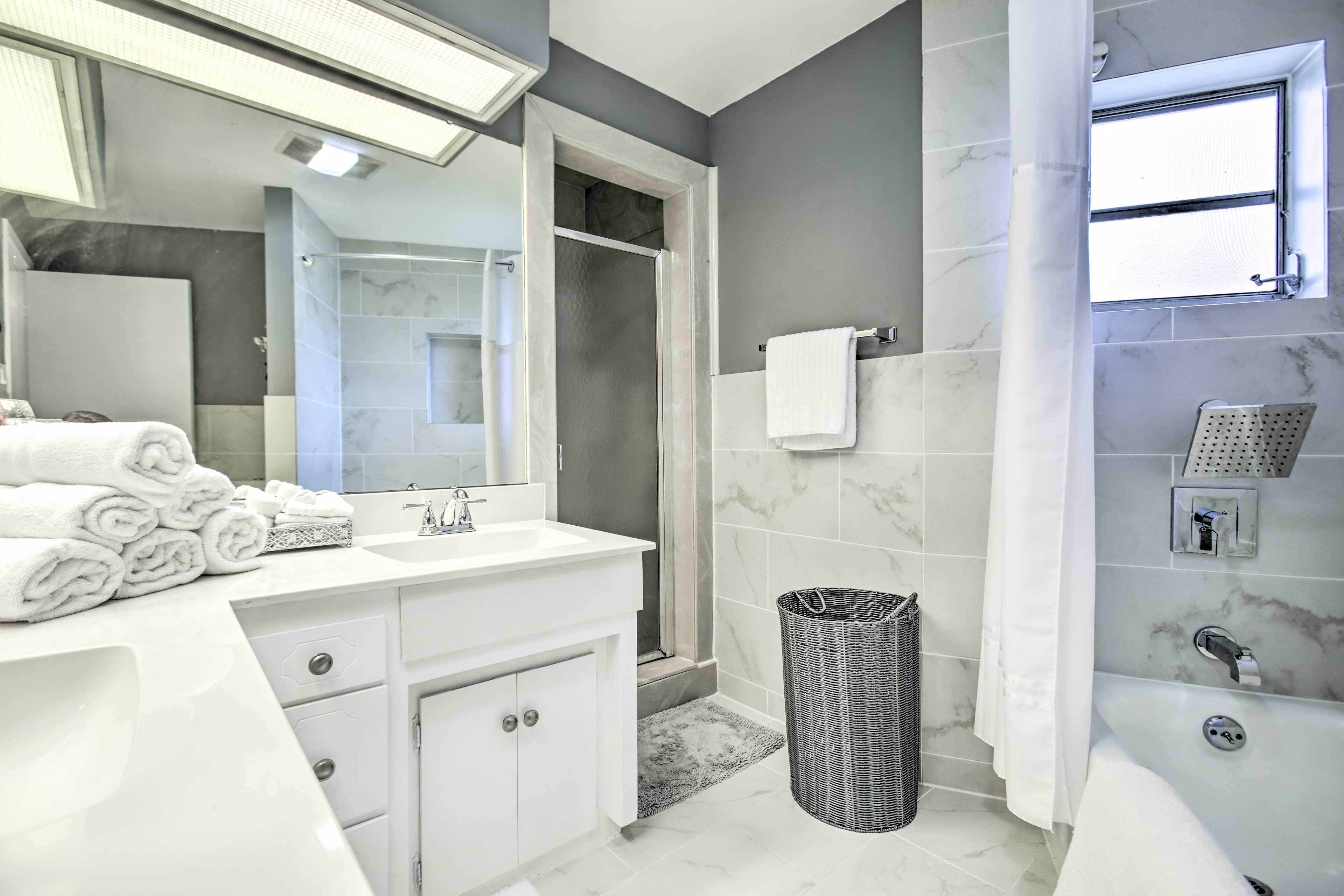 A modern bathroom with a white vanity, a large mirror, a shower area, and a bathtub.
