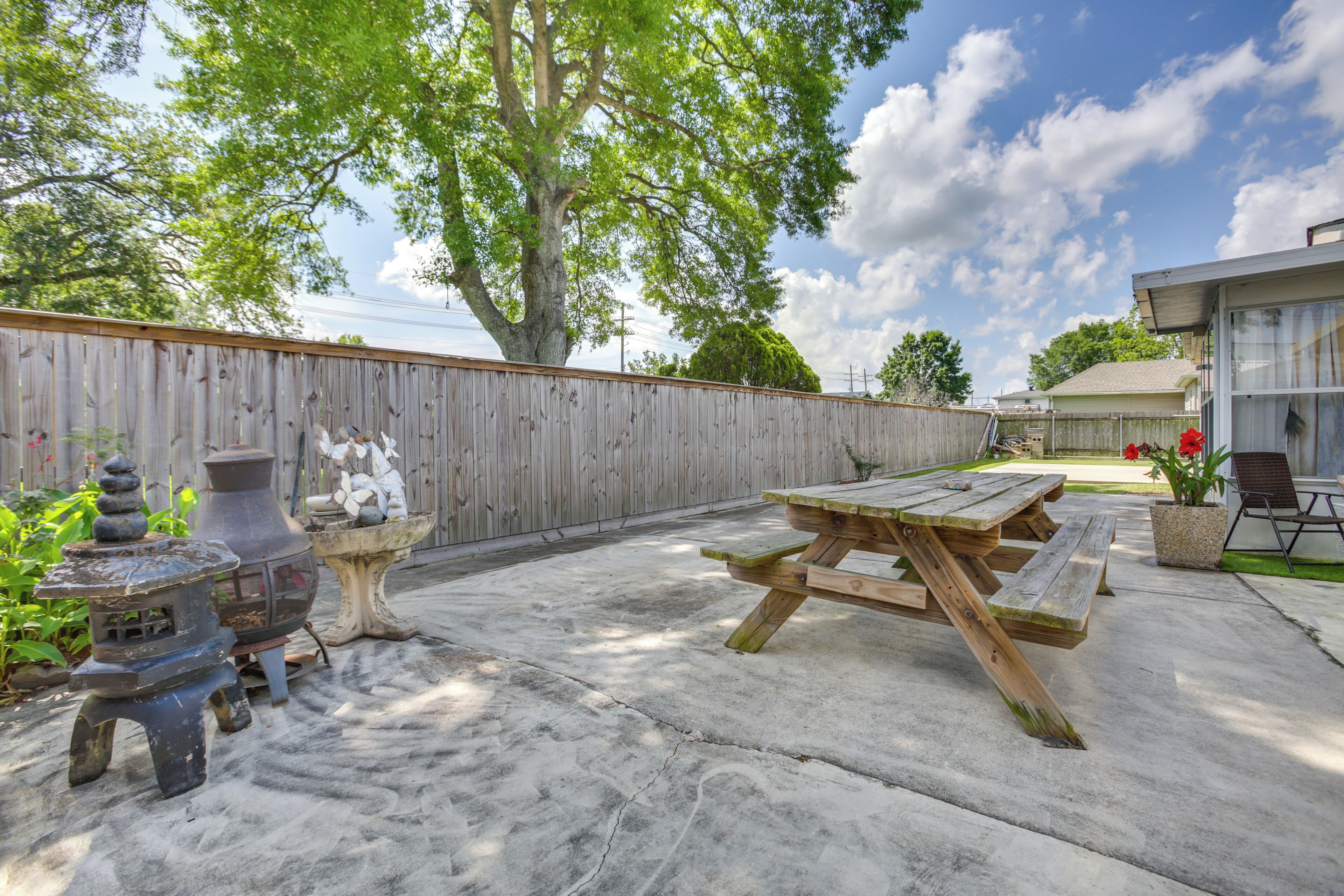 A backyard with a wooden fence, a picnic table, and a decorative stone lantern.
