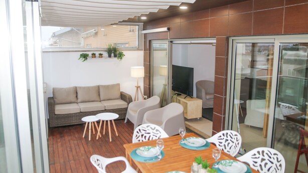 A dining area with a wooden table set for four, surrounded by white chairs.