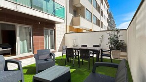 A courtyard with outdoor furniture, a building with balconies, and a clear sky.