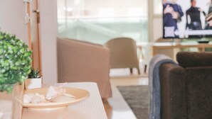 A modern living room with a sofa, a television, and a tray with decorative shells.
