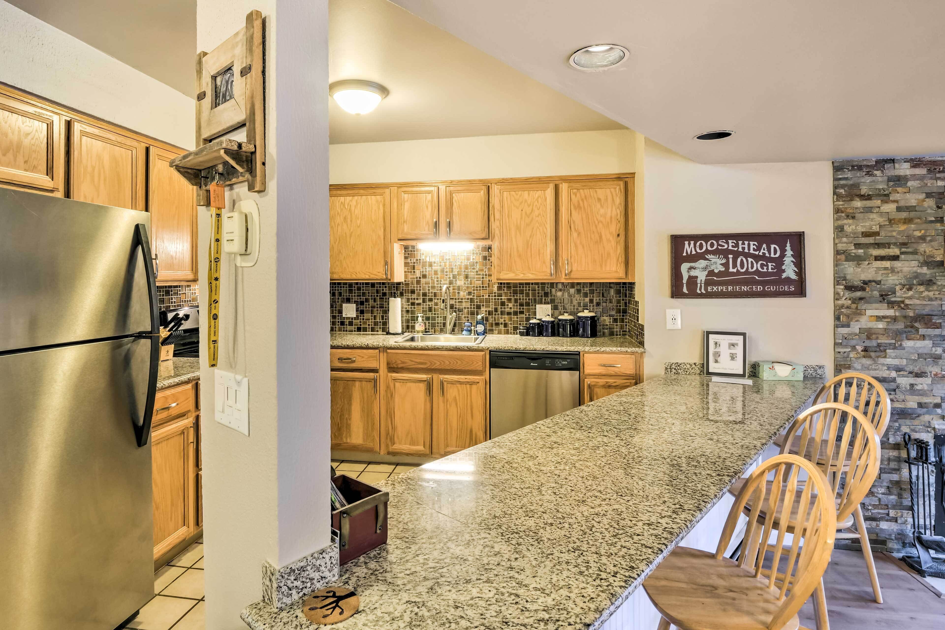A modern kitchen with wooden cabinets, a stainless steel refrigerator, granite countertops, and a stone backsplash.