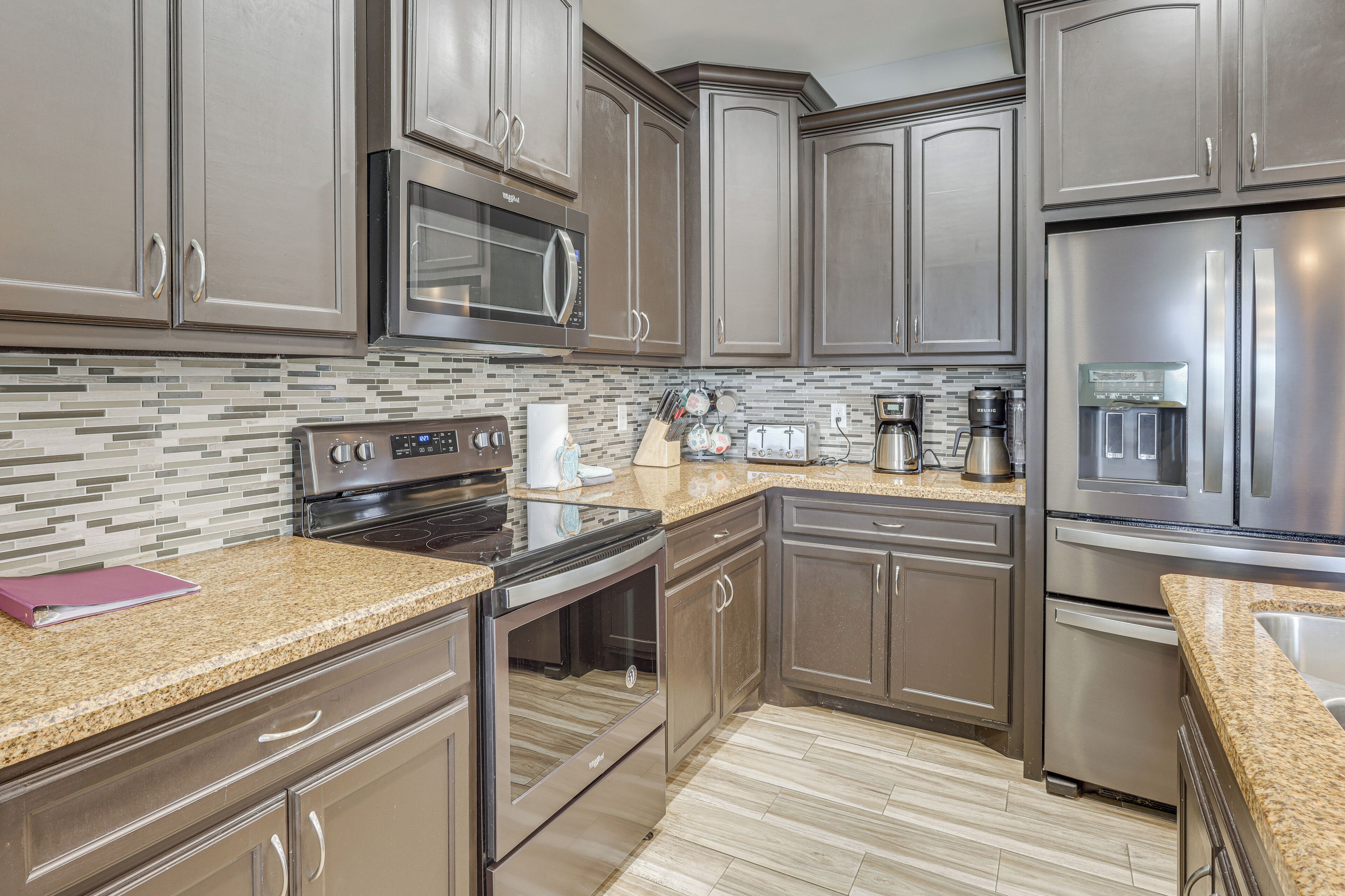 A kitchen with stainless steel appliances, granite countertops, and a tiled backsplash.