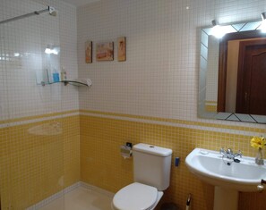 A bathroom with a toilet, sink, and shower area.