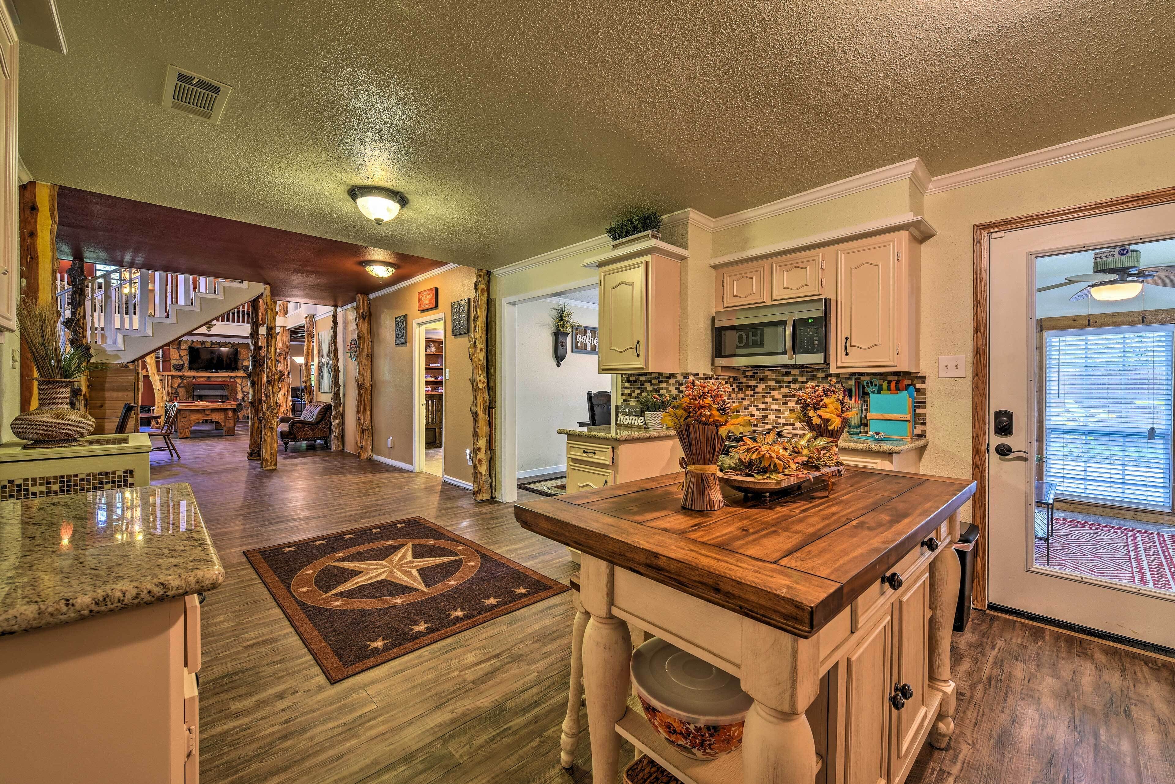 A kitchen with a wooden island, a microwave, and a sink. There is a staircase leading to another level.