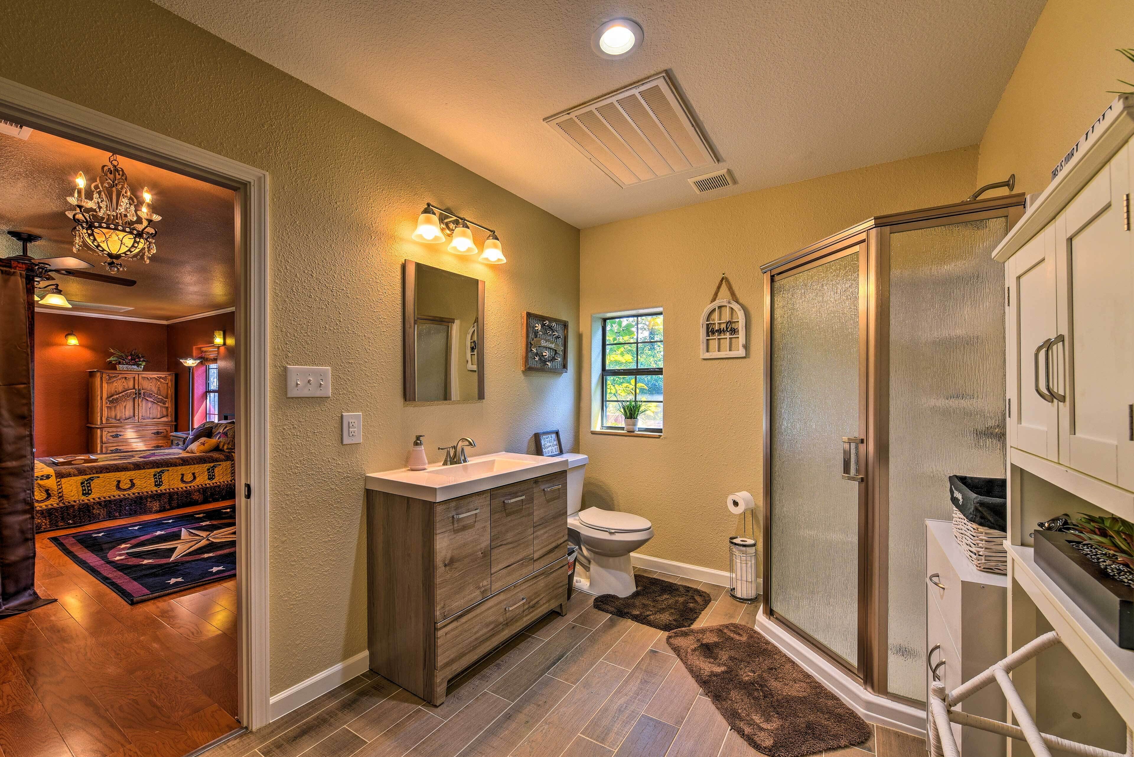 Une salle de bain comprenant un meuble-lavabo, des toilettes, une douche et une fenêtre.