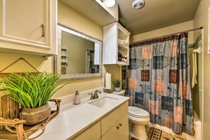 Bathroom features a sink, mirror, toilet, and shower with a decorative curtain.