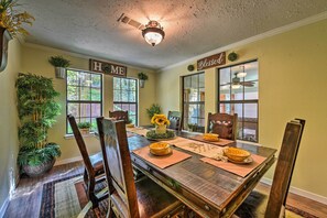 Enjoy meals with family and friends in this cozy dining area, featuring a long table set for six and a beautiful floral arrangement.