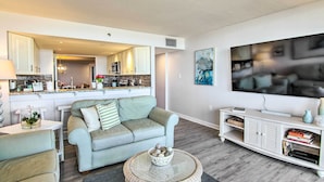 A modern living room with a light blue sofa, a round coffee table, and a white entertainment unit. - Indoor Pool & Views: Beachfront Ocean City Condo (Ocean City)