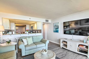 Uma sala de estar moderna com um sofá azul claro, uma mesa de centro redonda e um móvel de entretenimento branco.