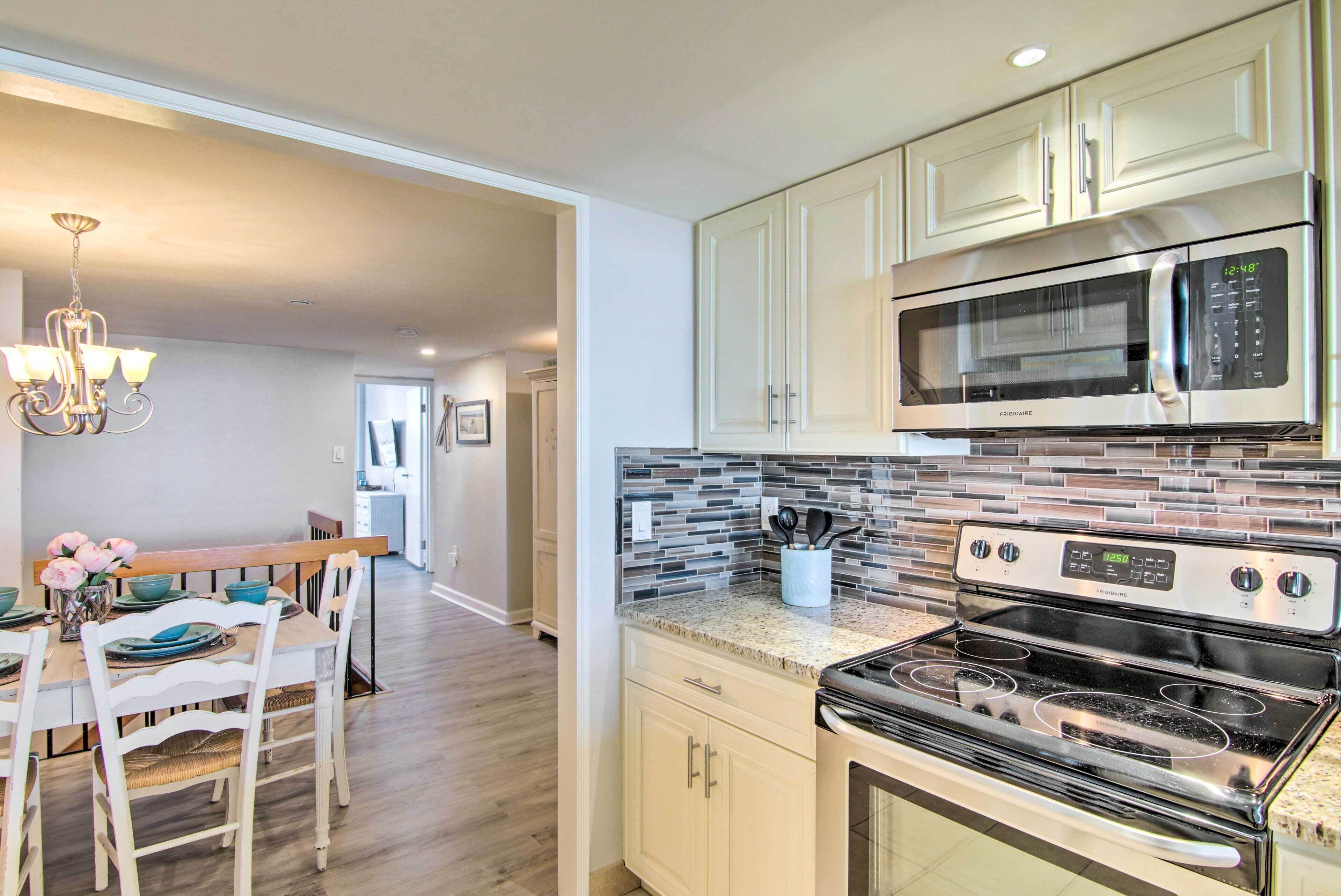 A modern kitchen with a built-in microwave, stove, and granite countertop.