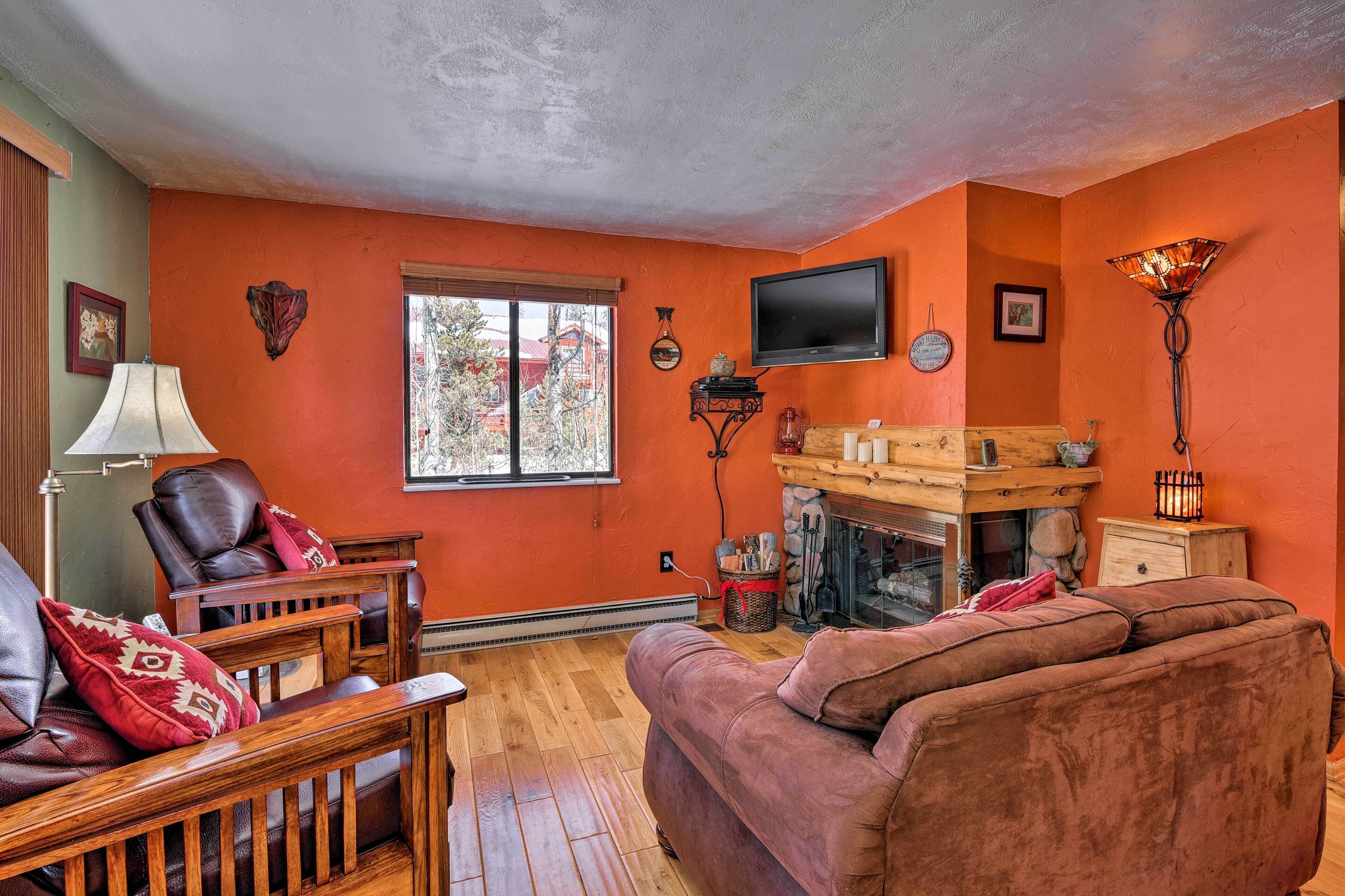 A living room with a fireplace, leather furniture, and an orange wall.