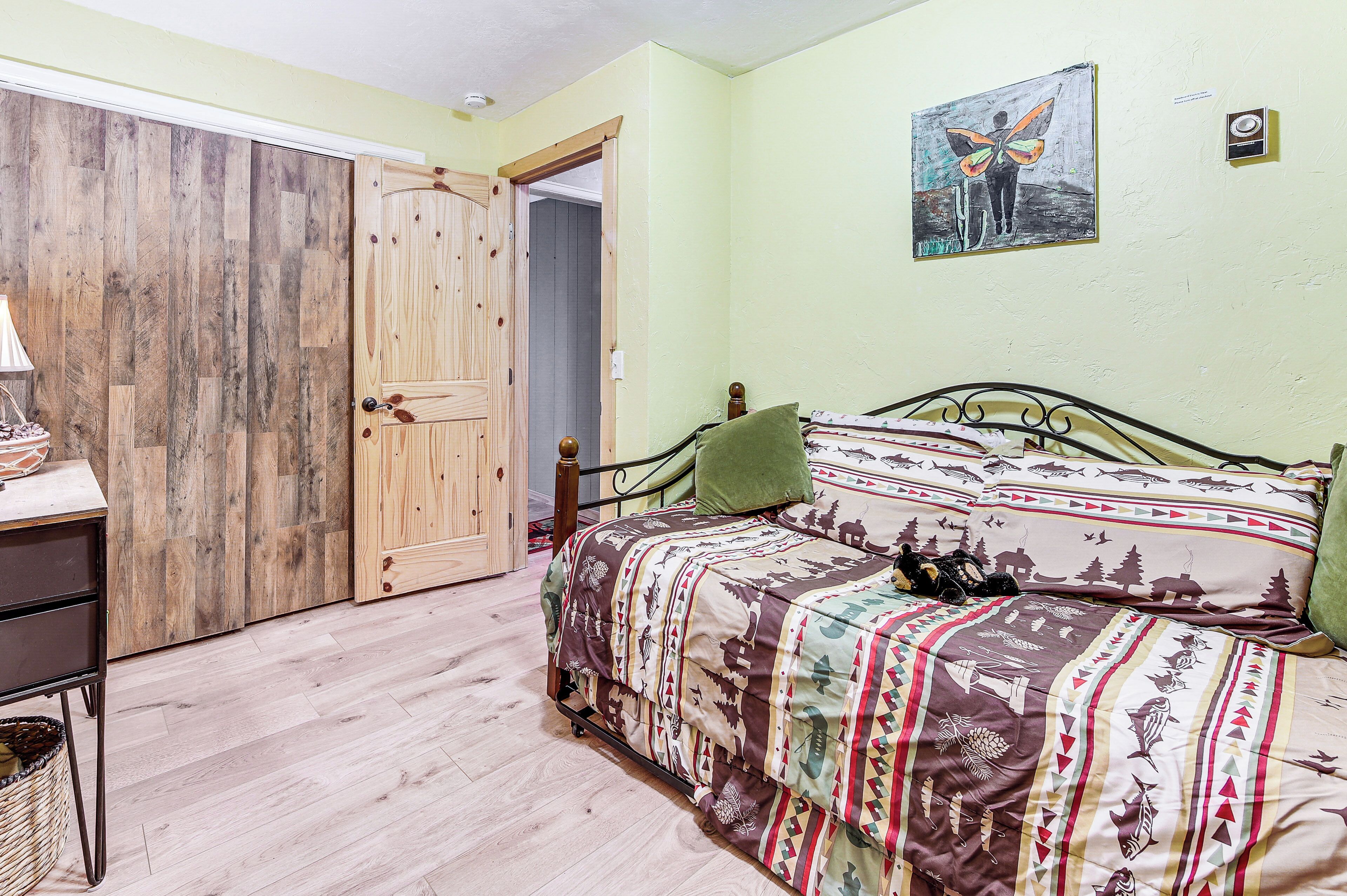 Un dormitorio con una cama, un armario de madera, un escritorio y un cuadro en la pared.