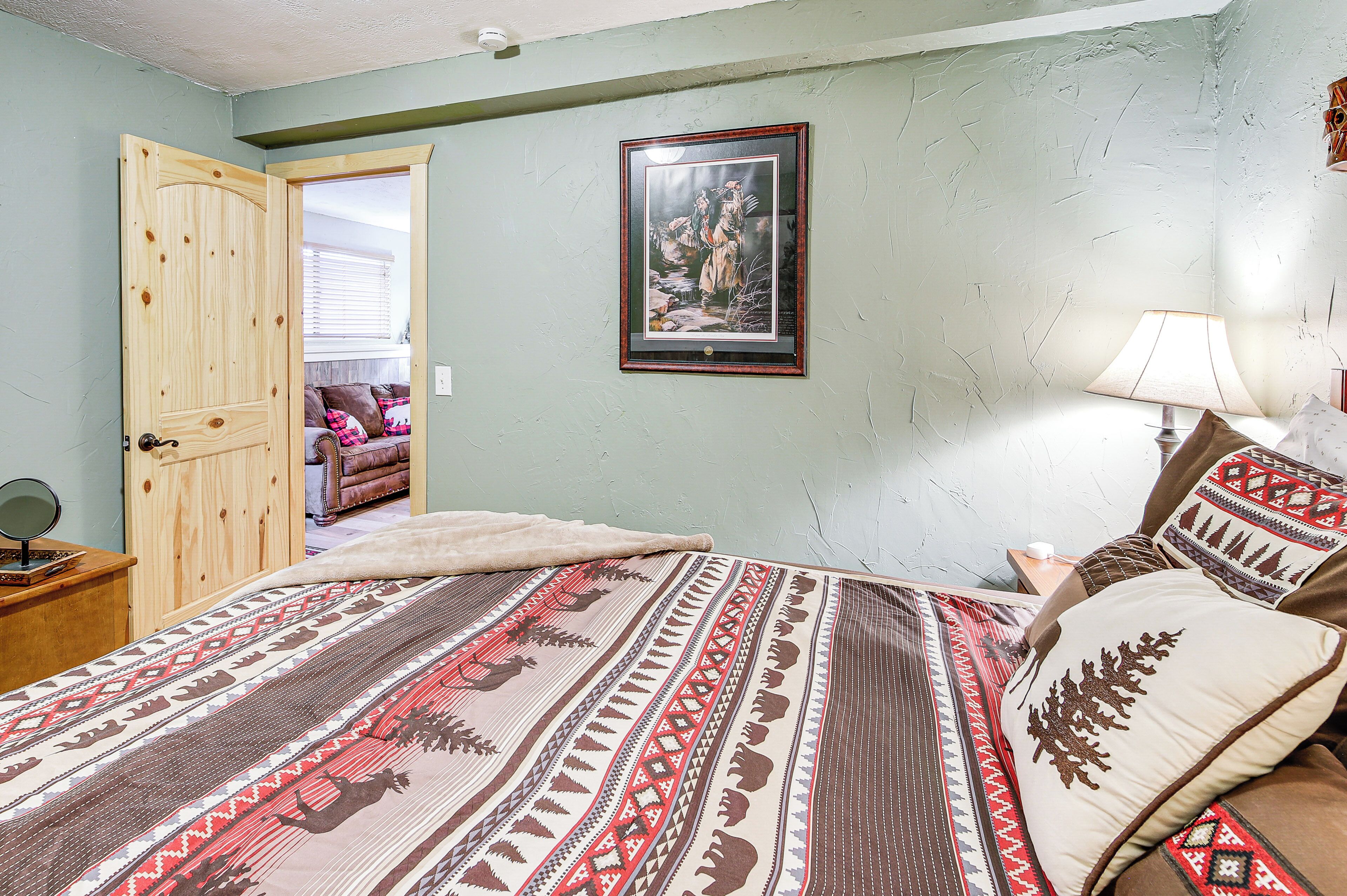 Une chambre à coucher avec un lit, une porte en bois, un tableau encadré au mur et une table de chevet avec une lampe.