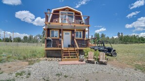 A two-story cabin with a balcony, a wooden deck, and a vehicle parked nearby. - Secluded Jefferson Cabin w/ Deck + Mountain Views! (Jefferson)