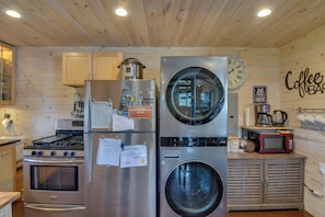 A compact kitchen with stainless steel appliances, a built-in washer and dryer, wooden cabinets, and a coffee bar area. - Secluded Jefferson Cabin w/ Deck + Mountain Views! (Jefferson)