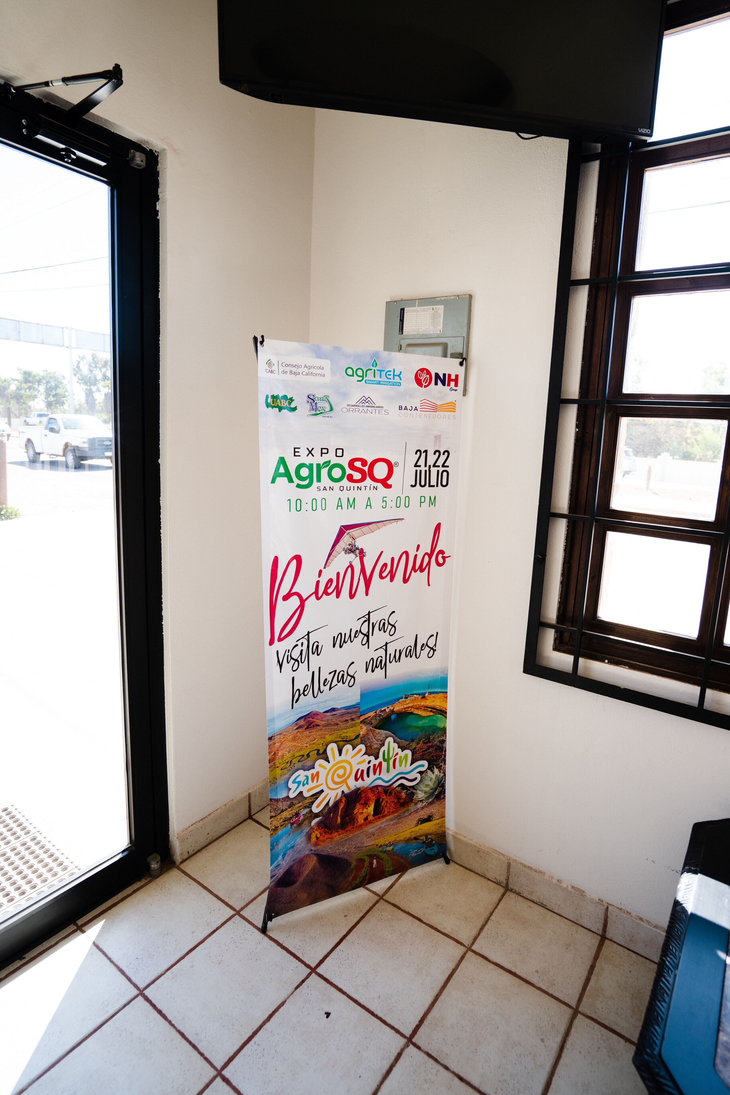 A promotional poster for an event, mounted on a wall near a window.