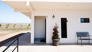 A modern building with a white exterior, a door, a potted plant, and a bench. - Hotel & RV PARK Rosa Evelyn (San Quintin)